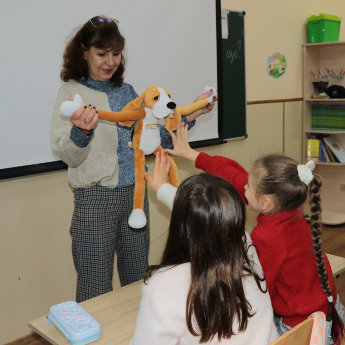 A teacher shows children the Hibuki doll in the form of a dog